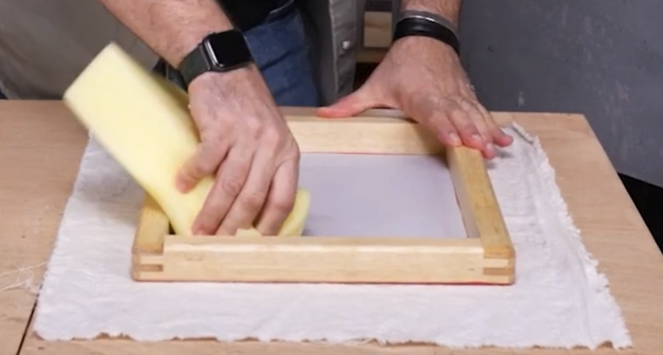 Coloque a tela sobre uma superfície plana. Retire o excesso de água pressionando suavemente com uma esponja. Não esfregue, apenas pressione para absorver a umidade.
