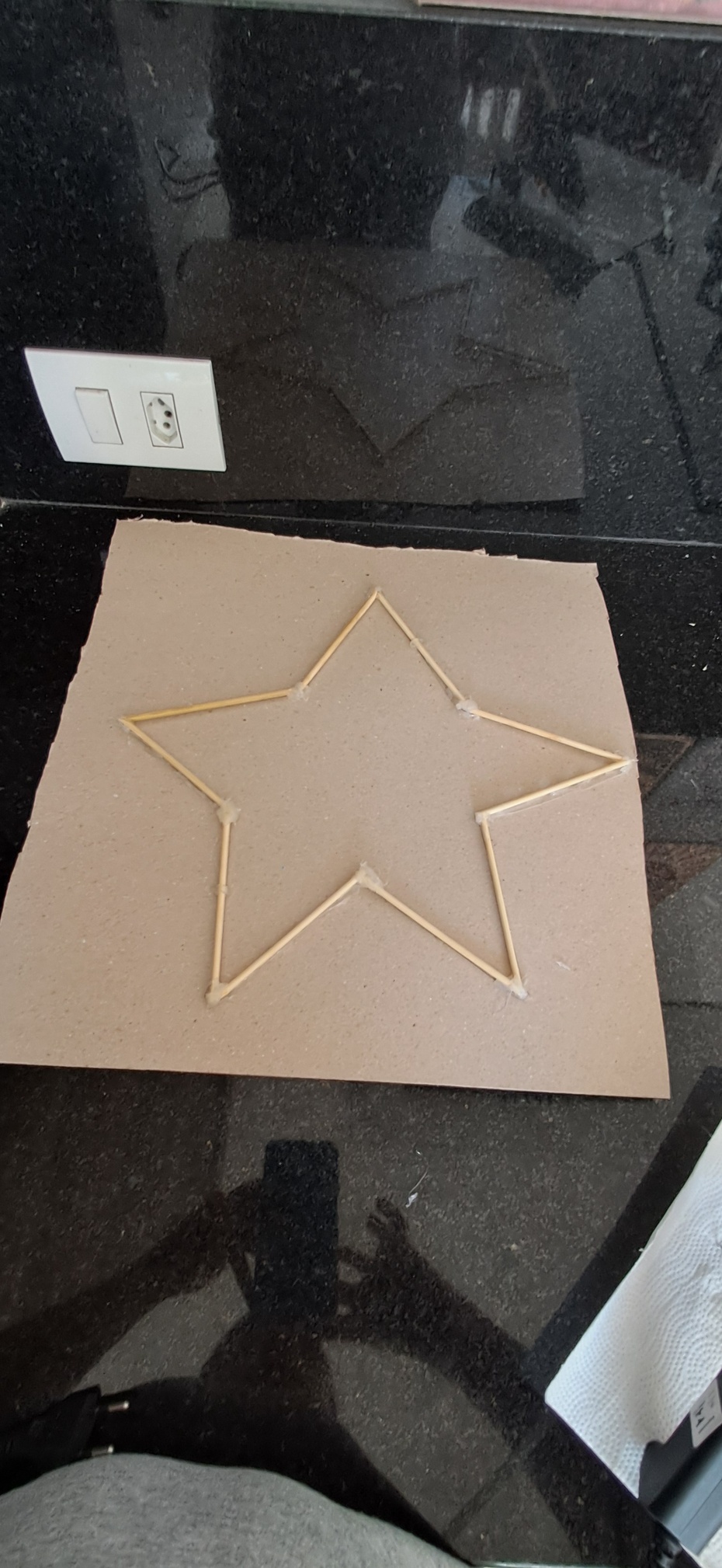 1- Pegue a estrela de palitos e o papel Paraná.
2- Posicione a estrela em um dos cantos do papel 
3- Marque o formato da estrela
4- Corte com a tesoura ou estilete.
5- cole atrás da estrela