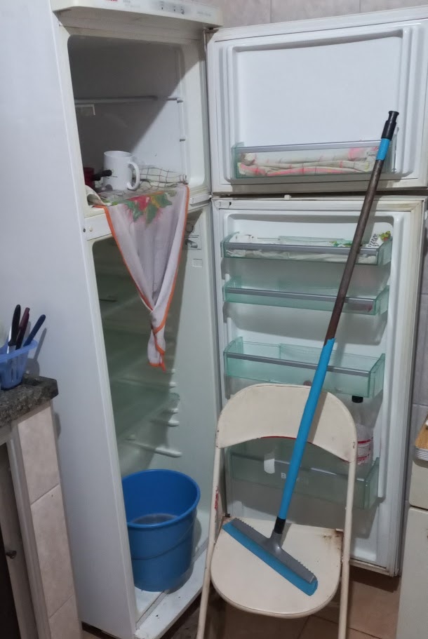 Acompanhe o descongelamento. Depois que os panos ficarem encharcados, a água de degelo deve pingar do pano suspenso em direção ao recipiente. A imagem abaixo foi obtida durante a primeira realização desse projeto, em 2023. As demais imagens aqui presentes utilizam uma geladeira frost free, e portanto são meramente ilustrativas.