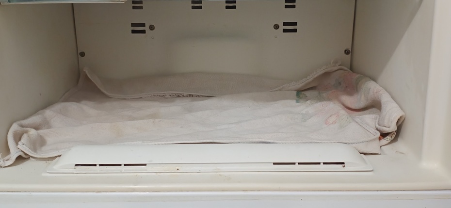 Atenção! Realize todo esse procedimento com a geladeira desligada para evitar acidentes. Coloque um pano de prato aberto na base do congelador. Esse pano ficará molhado à medida que o gelo for derretendo.