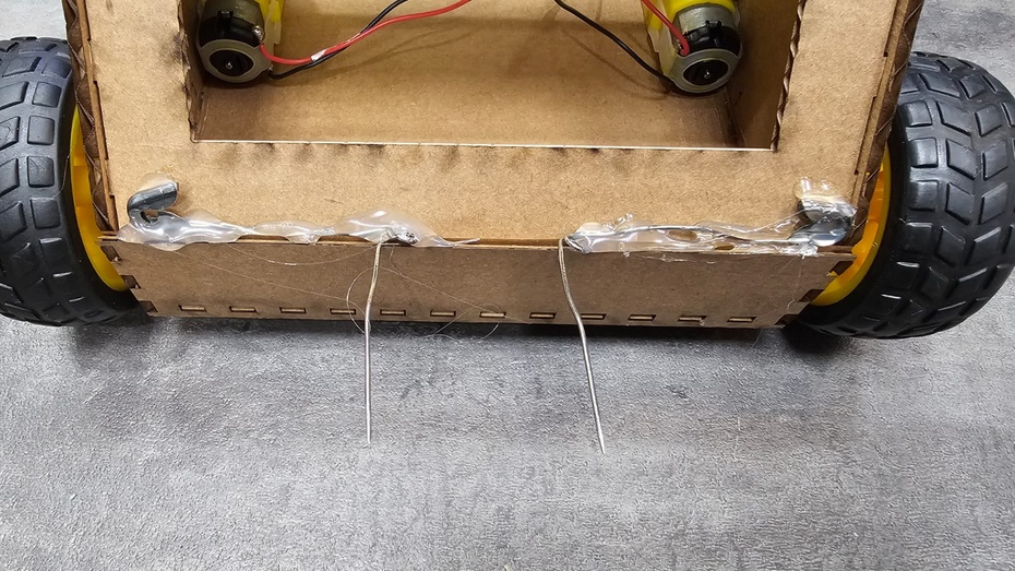 Abra em formato de “L” e cole os alfinetes acima do “para-choques” do carro. Pode passar uma quantidade boa de cola quente para que ele não saia facilmente. PEÇA AJUDA PARA UM ADULTO NESTA PARTE.