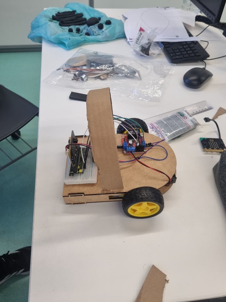 Separar todos os materiais elétricos

2x Micro:bit
Ponte H Dupla L298N
Protoboard
Motores DC
Suportes de pilha
Cabos jumper
Pilhas
Verifique se os motores e as pilhas estão funcionando corretamente.
Organizar os jumpers por tamanho para facilitar as conexões.
2. Fixação da estrutura
- Utilizar a placa de MDF como base do robô.
- Fixar:
- os motores,
- a roda boba,
- o suporte de pilhas,
- a ponte H L298N.
- Usar parafusos, cola quente ou super cola para manter tudo firme.
3. Montagem da alimentação elétrica
Inserir as pilhas nos suportes.
Conectar o suporte de pilhas 4.2V na entrada de alimentação da ponte H L298N:
fio positivo no pino 12V/VCC,
fio negativo no GND.
Garantir que a polaridade esteja correta para evitar danos.
4. Conexão dos motores na ponte H
Conectar:
Motor esquerdo nas saídas OUT1 e OUT2,
Motor direito nas saídas OUT3 e OUT4 da L298N.
Apertar bem os terminais para evitar mau contato.
5. Ligação do Micro:bit à ponte H
Utilizar cabos jumper para conectar:
pinos digitais do Micro:bit nos pinos de controle da L298N.
Exemplo:
P0 → IN1
P1 → IN2
P2 → IN3
P8 → IN4
Conectar também:
GND do Micro:bit ao GND da ponte H.
6. Utilização da protoboard
Usar a protoboard para:
organizar conexões,
distribuir energia,
facilitar testes.
Evitar fios cruzados para melhorar a manutenção.
7. Programação do Micro:bit
Conectar o Micro:bit ao computador usando o cabo USB.
Utilizar o software Microsoft MakeCode para programar:
movimentação para frente,
ré,
curvas,
parada dos motores.
Transferir o código para o Micro:bit.