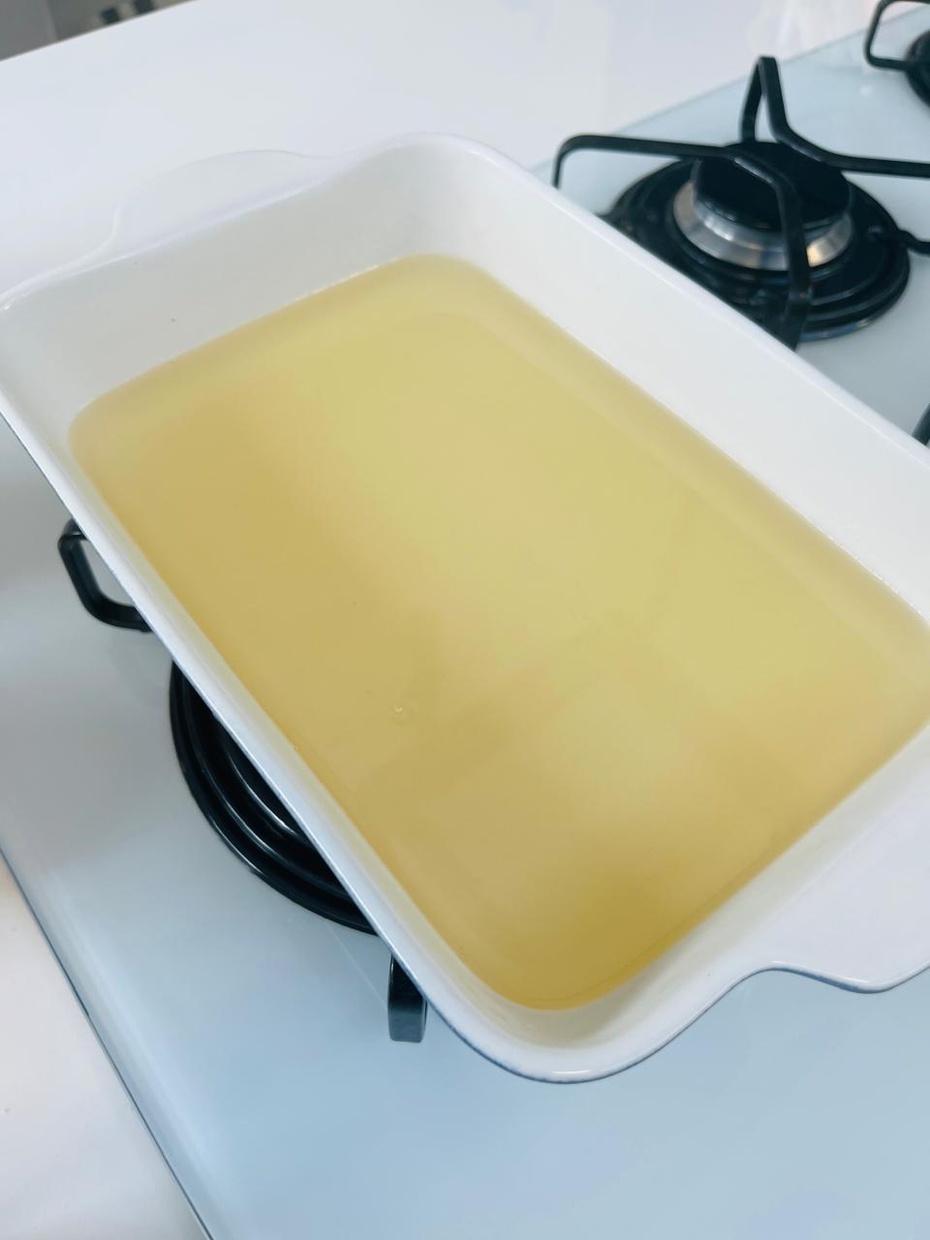 Despejar o líquido ainda quente em um recipiente de vidro ou louça até uma altura de 1 a 2 cm de líquido.