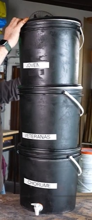 Monte a pilha: coloque o balde coletor (com torneira) no chão; encaixe o balde intermediário (com tampa perfurada presa) em cima; encaixe o balde superior (também com a tampa perfurada presa) em cima. Por fim, coloque a tampa ventilada.