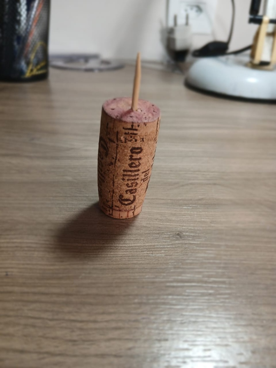 pegue um palito, parta ele no meio e fure a rolha com a parte mais pontuda para cima