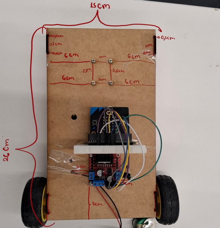 Circuito na Base:
Depois da montagem devesse encaixar o circuito com o microbit a 5 centimetros da base de 15 cm e centralizado com o arduino sendo posicionado de maneira vertical para ser possivel colocar o galão de agua dentro dele. Para a conexão do circuito com as rodas será necessario fazer furos para que os fio cheguem a parte de baixo do robô para conectar com as rodas,  o furo foi feito a 2cm de distancia do microbit (distância irrelevante, pode variar sem nenhum problema)