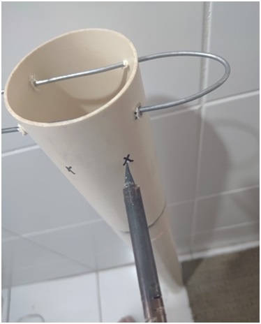 Repita o mesmo procedimento alguns centímetros (acima ou abaixo) para passar a segunda haste metálica / arame de cabide, sempre mantendo abaixo da marca do nível da terra.