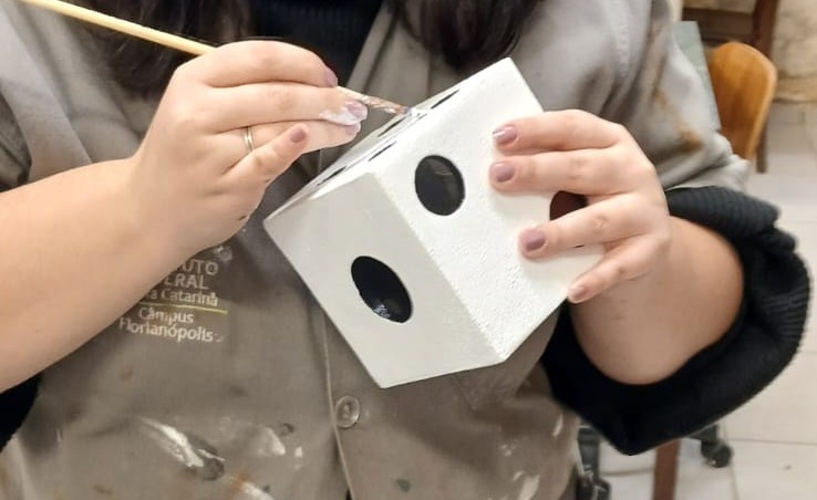 Na etapa de pintura, aplicaram-se algumas camadas de tinta acrílica branca na parte externa, enquanto a parte interna recebeu tinta acrílica preta, ambas utilizando a técnica do esponjado. Contudo, nos cantos e arestas, a aplicação foi feita com o auxílio de um pincel.